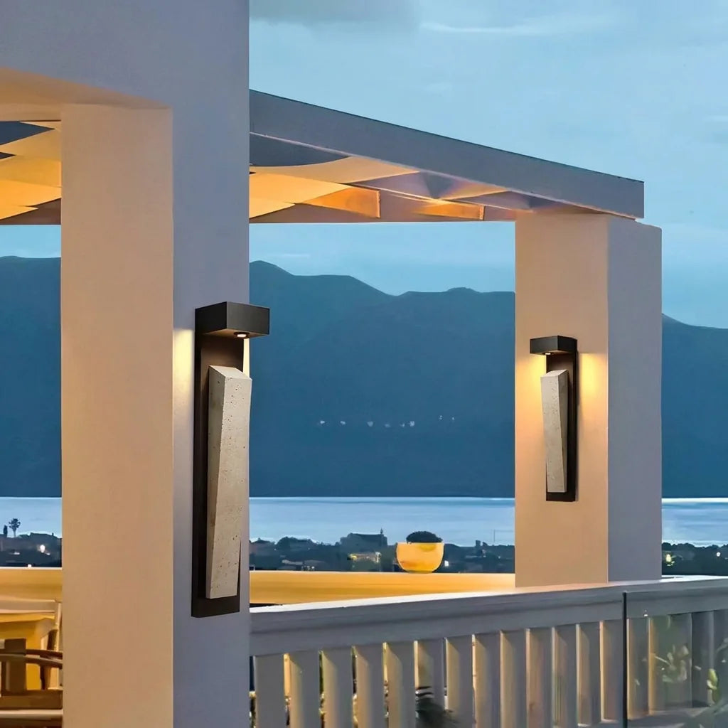 Deux appliques en travertin sur les piliers d'une terrasse avec vue mer