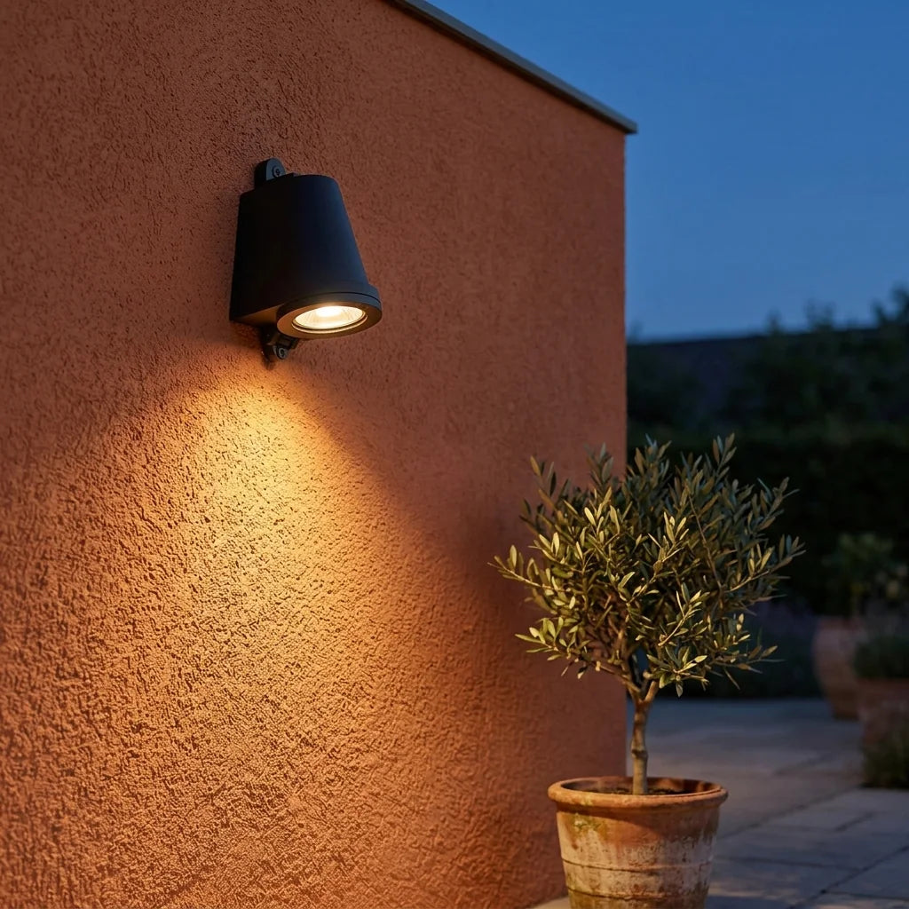 Applique cloche noire sur une façade en enduit terracotta au crépuscule