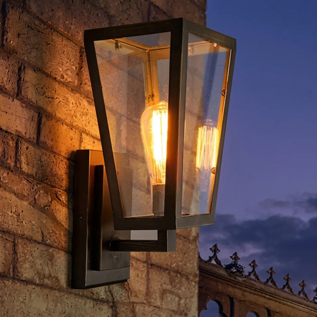 Applique lanterne trapèze orientée vers le haut sur un mur en briques au crépuscule