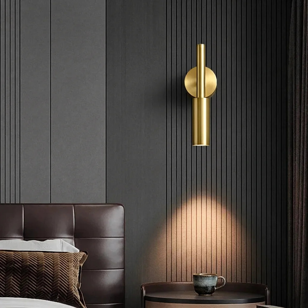 Applique liseuse dorée sur un mur à lames gris foncé près d'une tête de lit en cuir