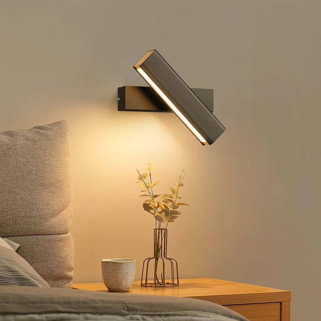 Applique barre LED rotative noire au-dessus d'une table de chevet en bois