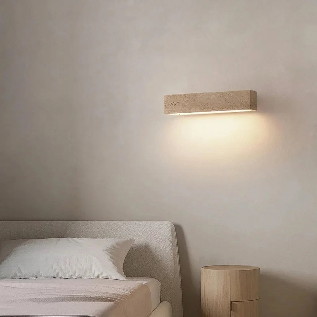 Applique barre en travertin éclairant une chambre épurée