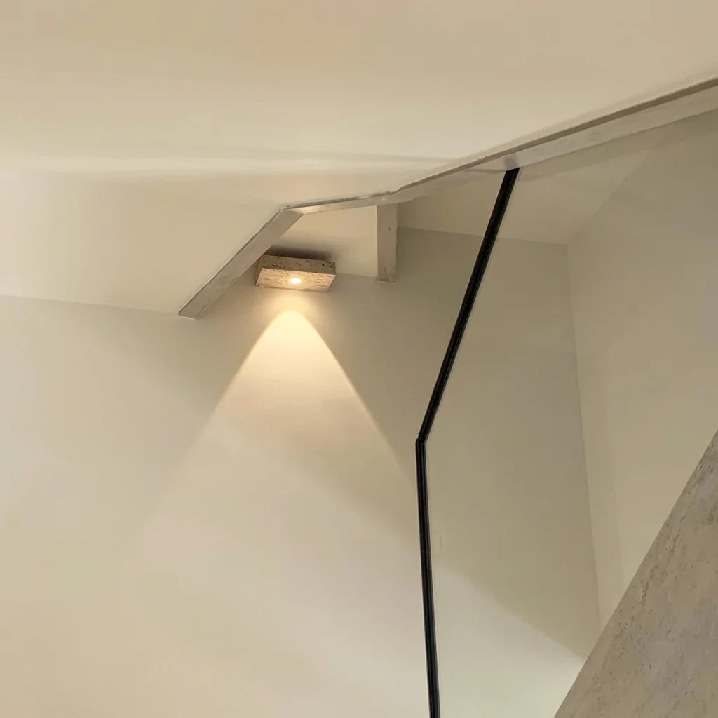 Applique en travertin éclairant une cage d'escalier crème