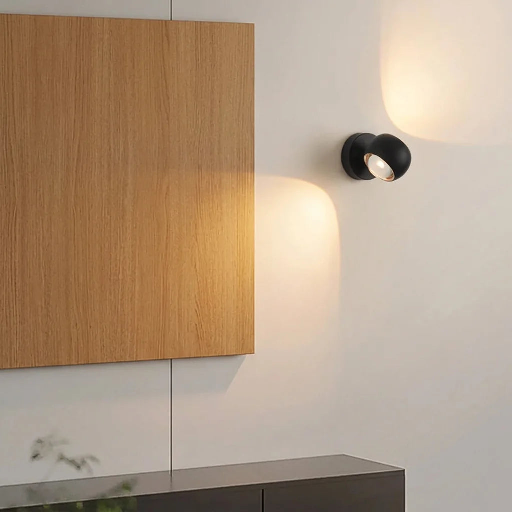 Applique boule noire orientée vers un panneau en bois dans un salon