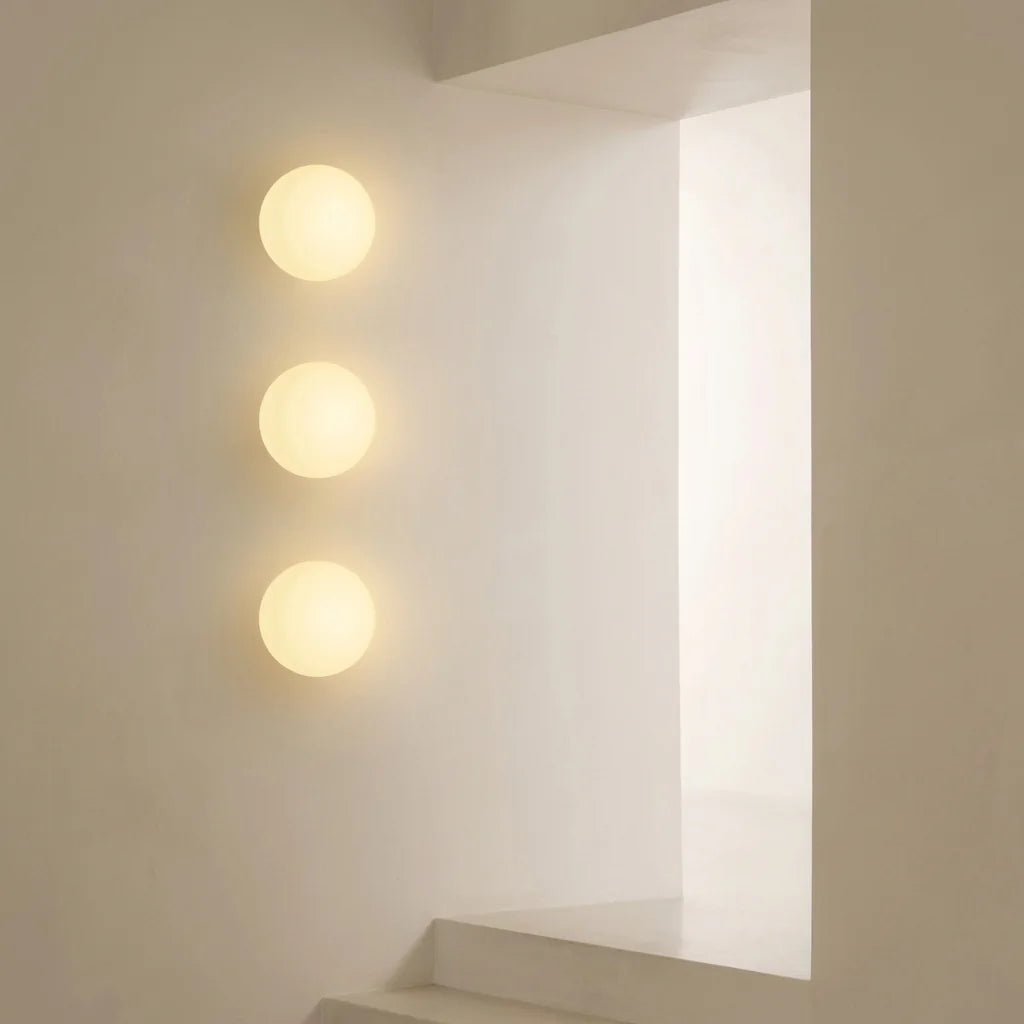 Trois appliques boule opaline superposées dans une cage d'escalier