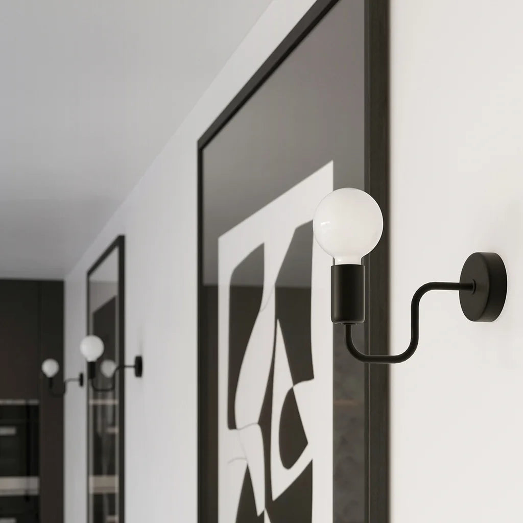 Applique murale bras tubulaire coudé noir dans un salon
