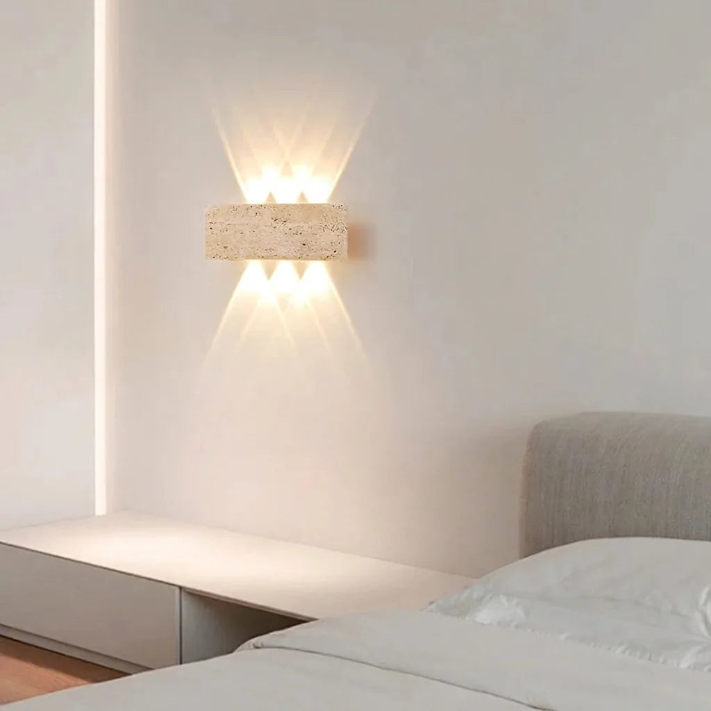 Applique en travertin au-dessus d'un lit, chambre blanche épurée