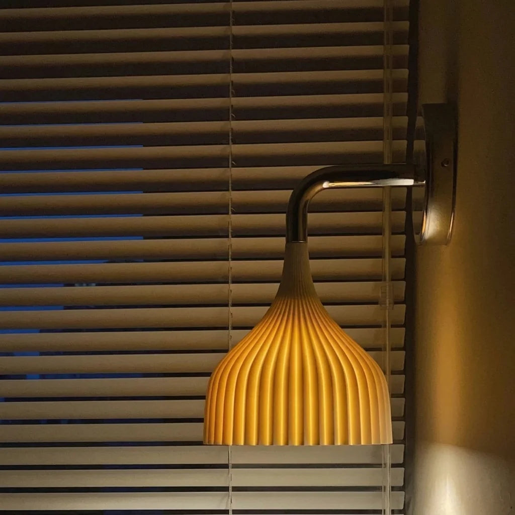 Applique cloche nervurée blanche allumée devant des stores en bois