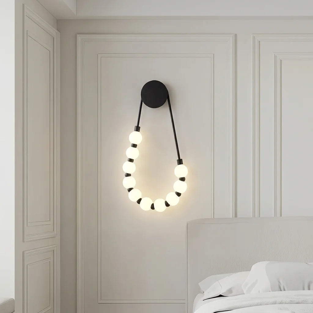 Applique collier de perles noire sur un mur à moulures près d'un lit
