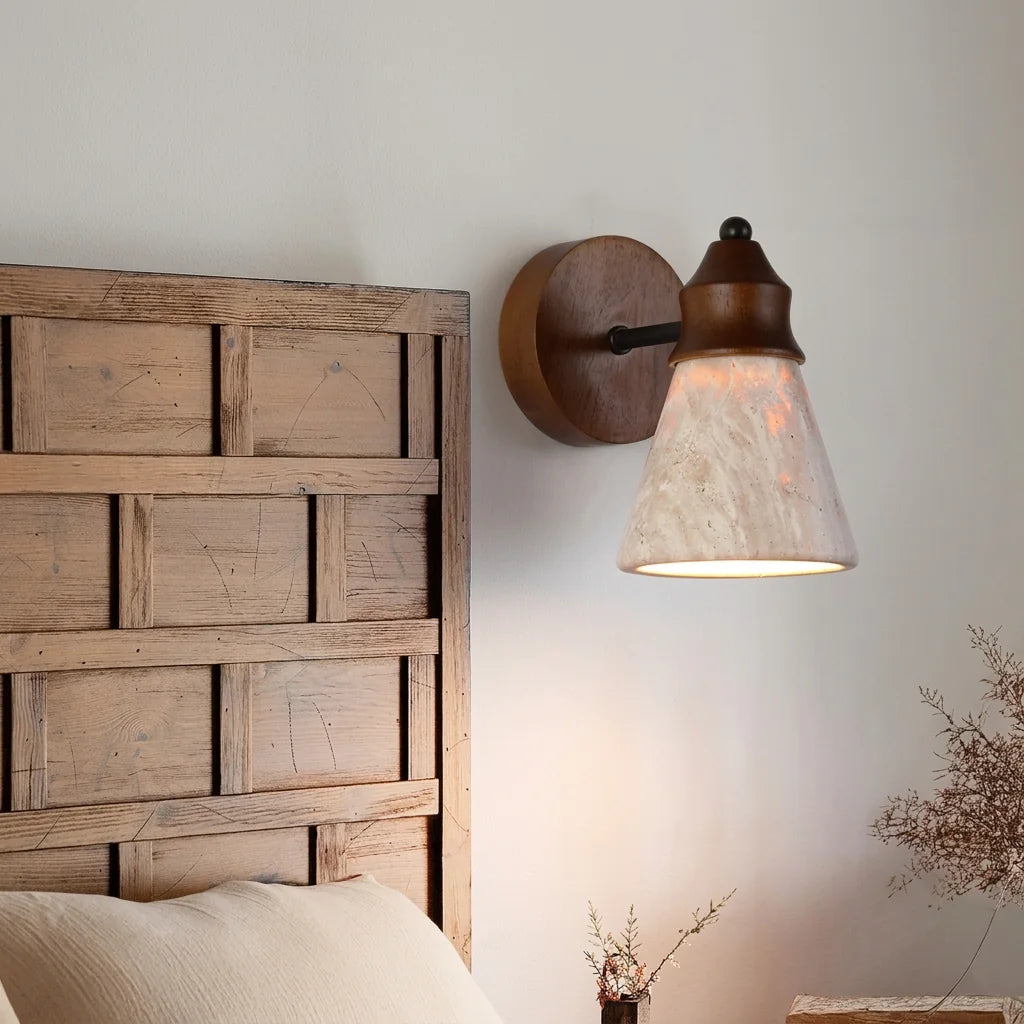 Applique cône en travertin à côté d'une tête de lit en bois de récupération