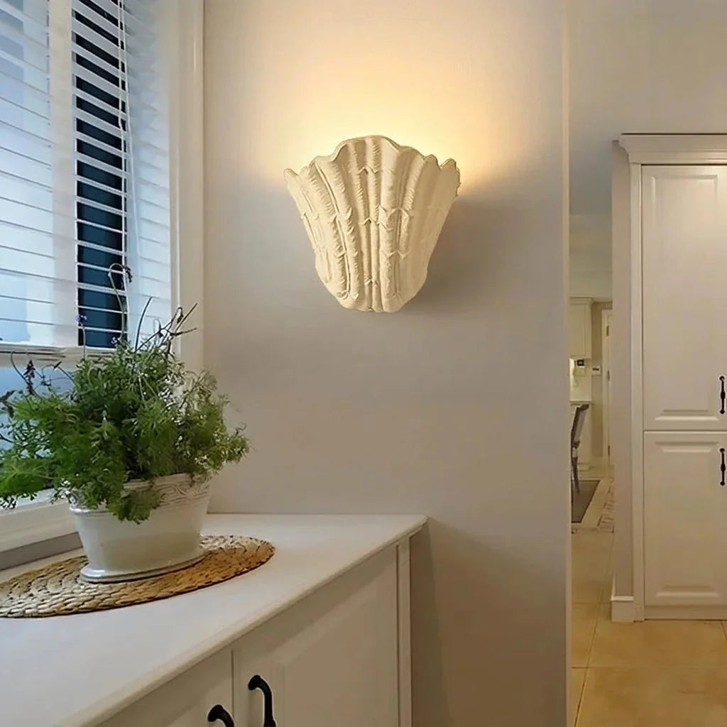 Applique coquillage beige allumée au-dessus d'un meuble d'entrée