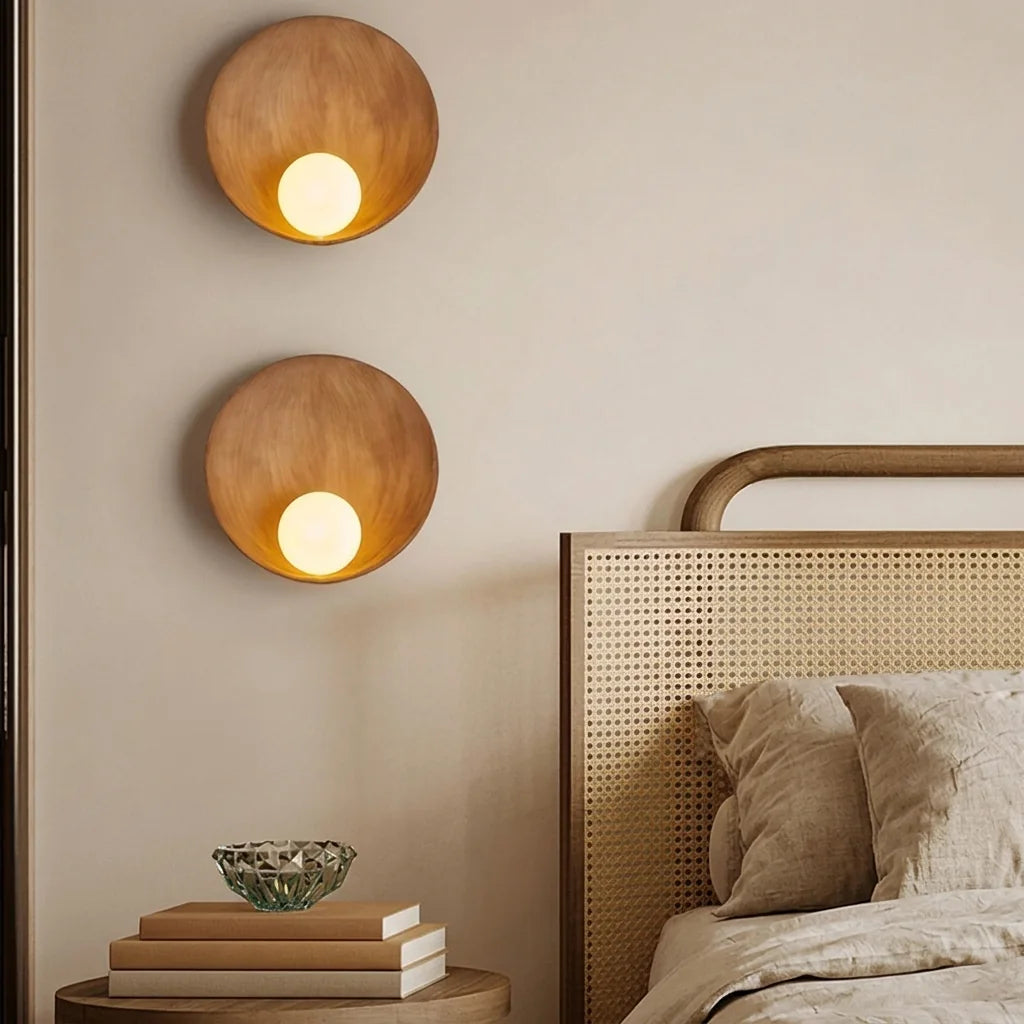 Deux appliques coupelle aspect bois près d'une tête de lit cannée