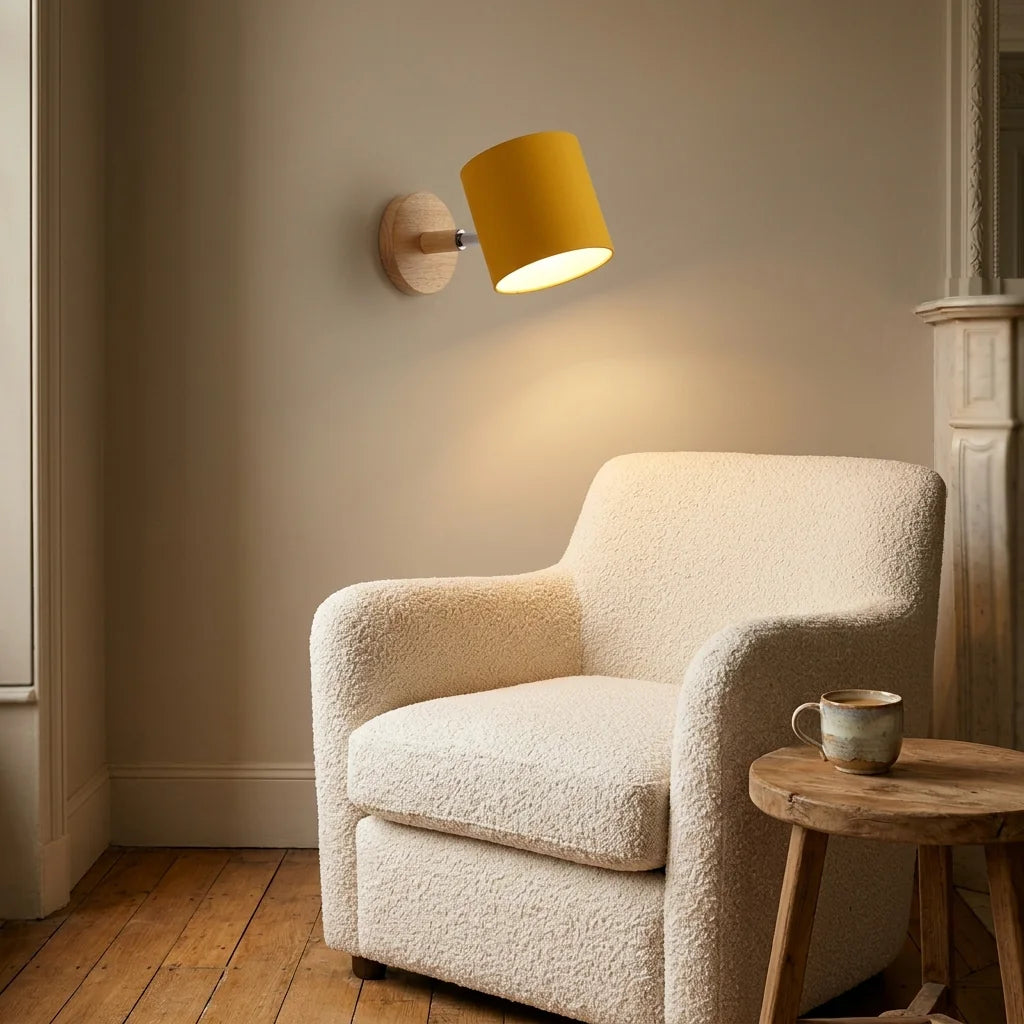 Applique cylindre jaune moutarde au-dessus d'un fauteuil bouclette