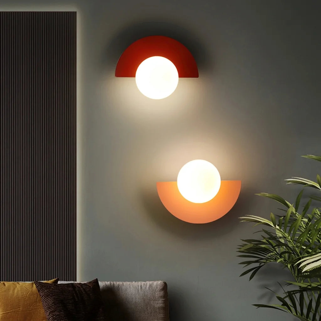 Appliques demi-lune rouge et rose sur un mur gris au-dessus d'un canapé