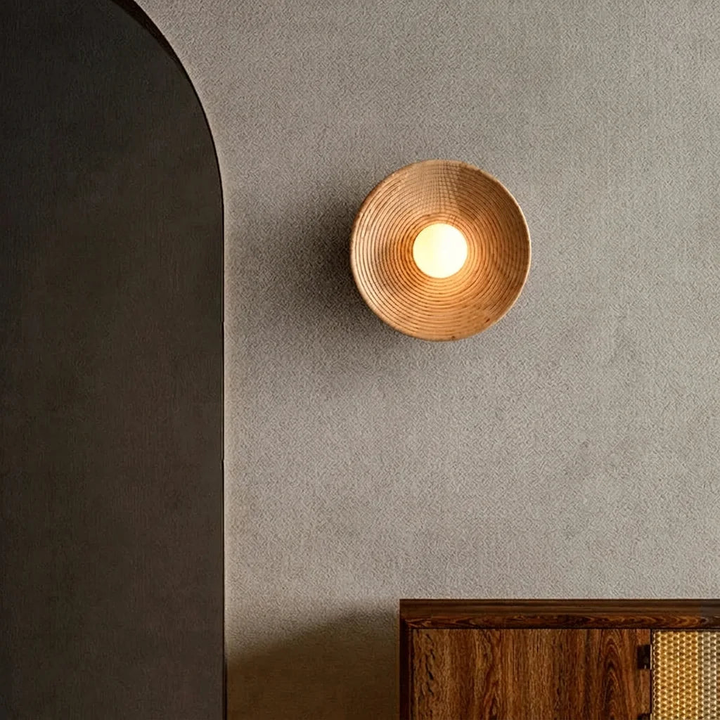 Applique coupelle en bois sur un mur enduit gris près d'une arche