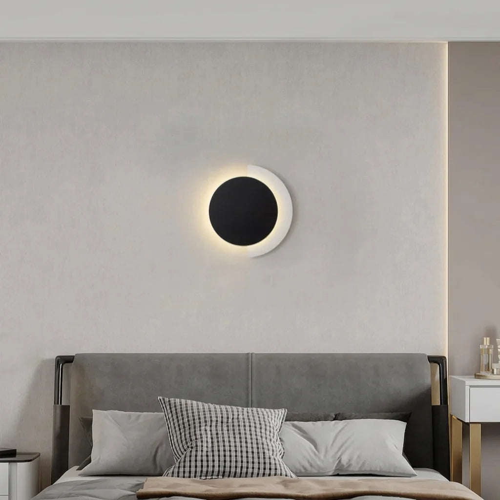 Applique disque noir et croissant blanc au-dessus d'un lit gris