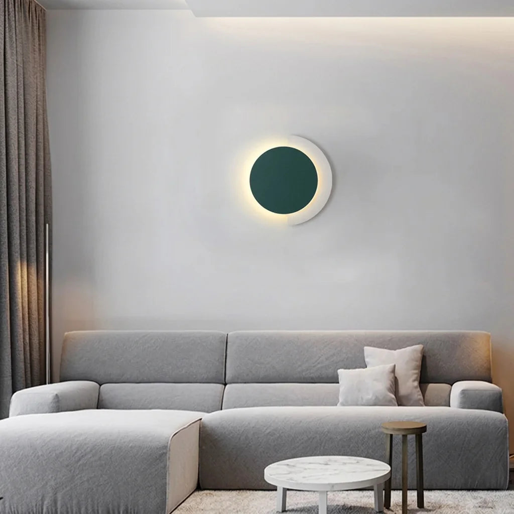 Applique disque vert et croissant blanc au-dessus d'un canapé gris