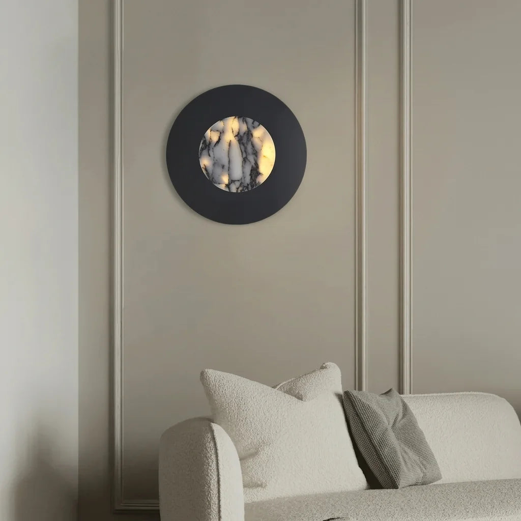Applique disque noir et marbre sur un mur à moulures au-dessus d'un canapé bouclette
