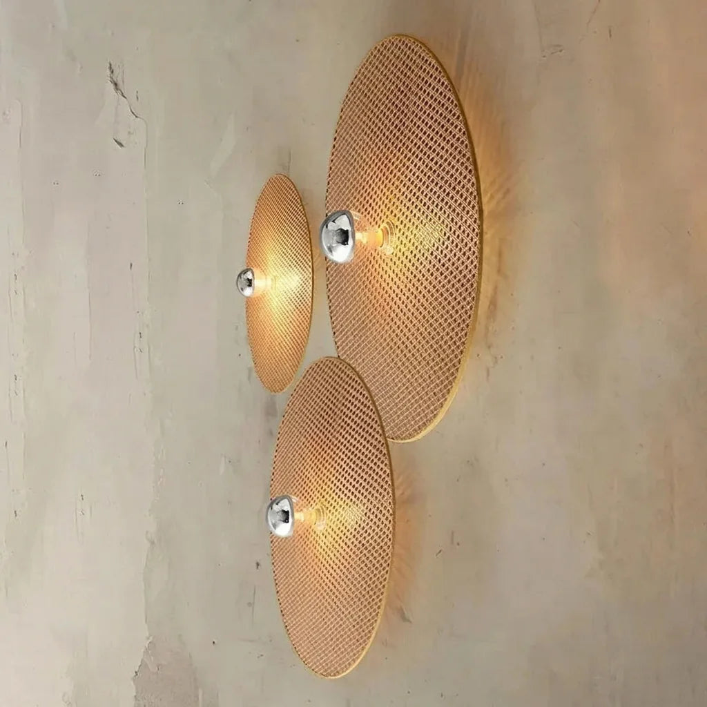 Composition de trois appliques disque en rotin sur un mur brut