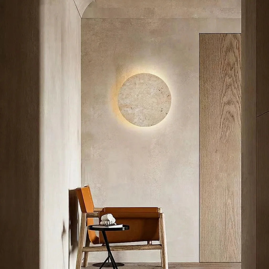 Applique disque en travertin dans un couloir en enduit, fauteuil en cuir