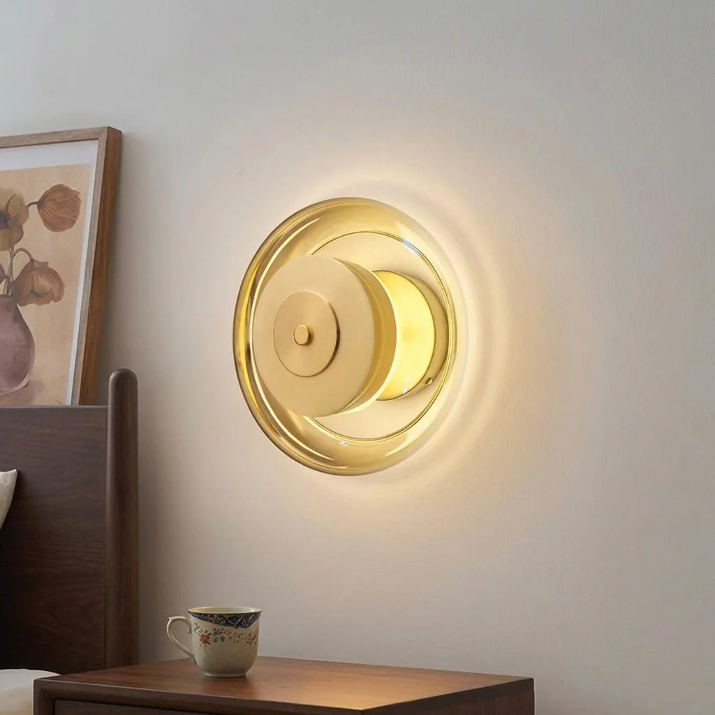 Applique disque en verre doré au-dessus d'une table de chevet en bois