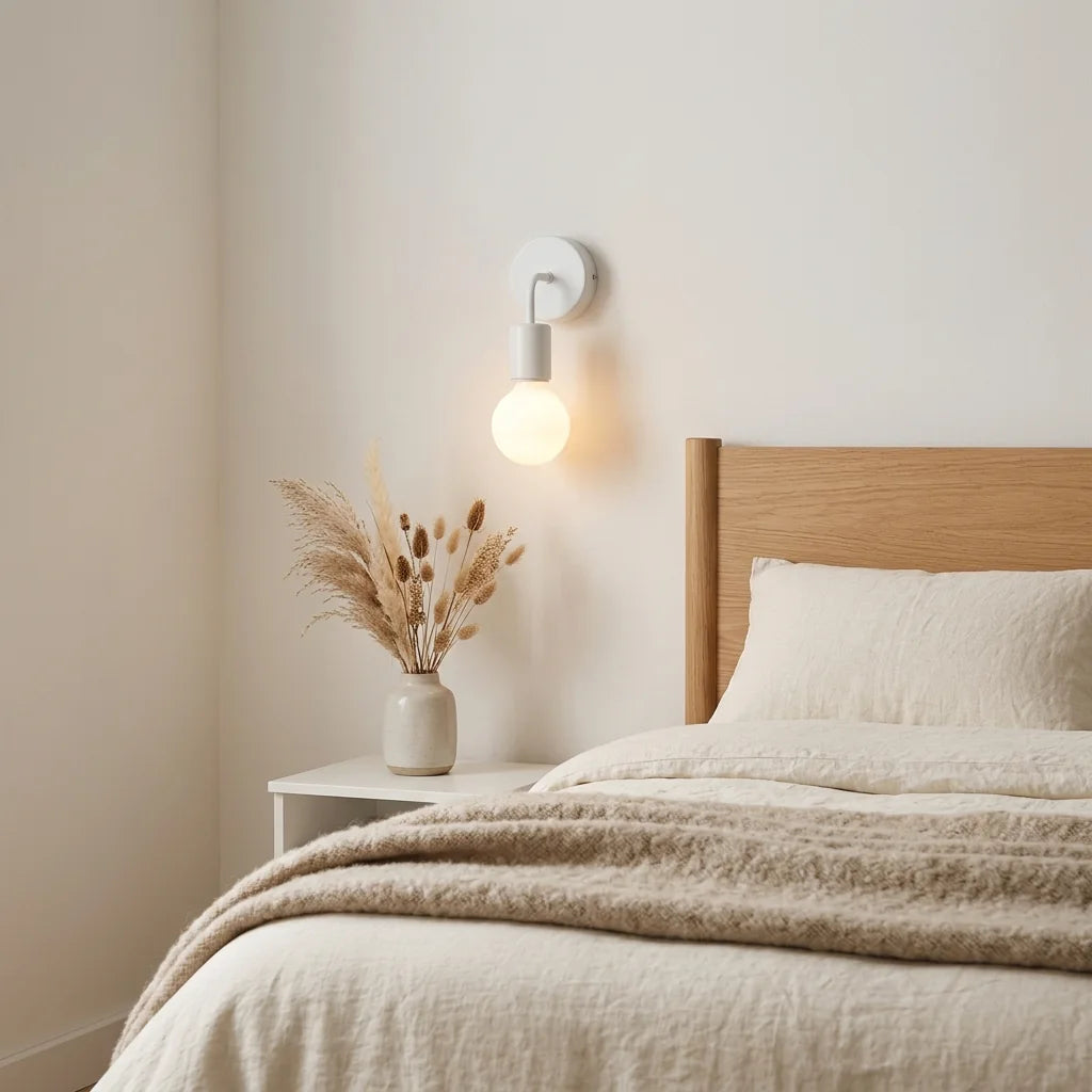 Applique blanche minimaliste au-dessus d'une table de chevet