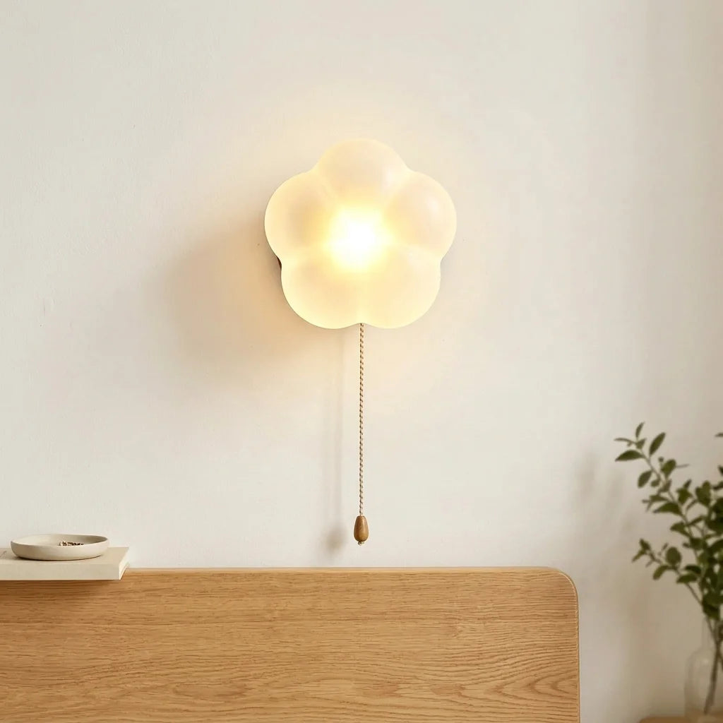 Applique fleur opaline allumée au-dessus d'une tête de lit en chêne