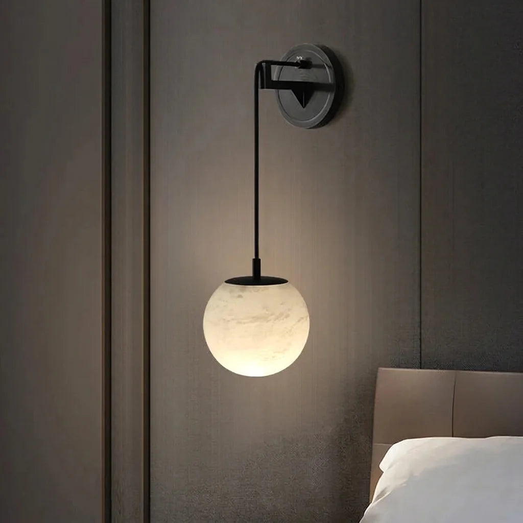 Applique globe en albâtre et métal noir au-dessus d'une tête de lit
