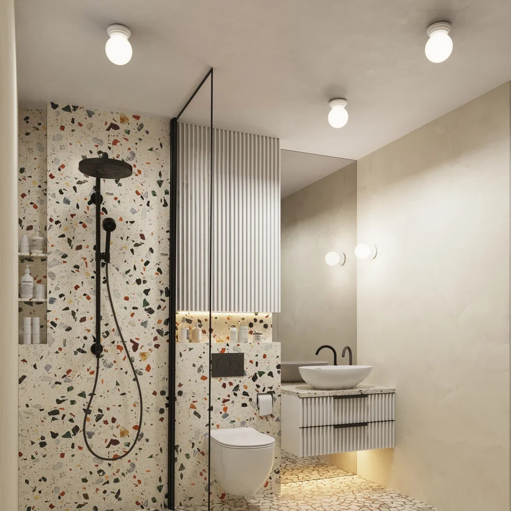 Applique murale globe opale sur rosace en céramique émaillée dans une salle de bain