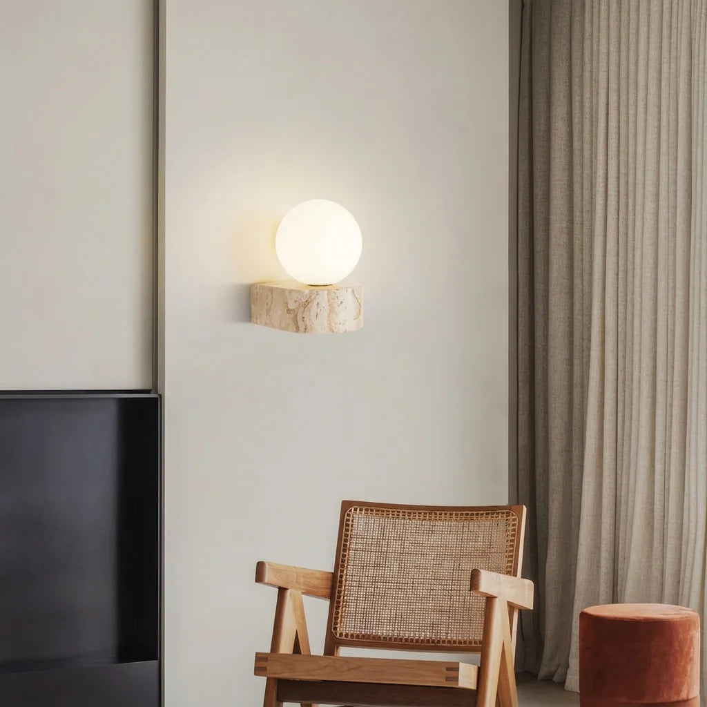 Applique globe sur travertin au-dessus d'un fauteuil cannelé et d'un pouf terracotta