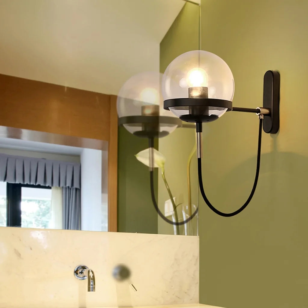 Applique globe noire allumée près d'un miroir de salle de bain