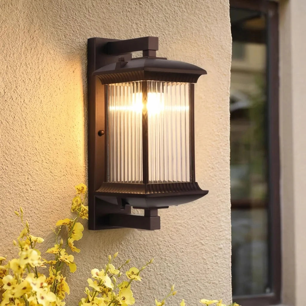 Lanterne extérieure en verre strié sur un mur enduit, fleurs jaunes