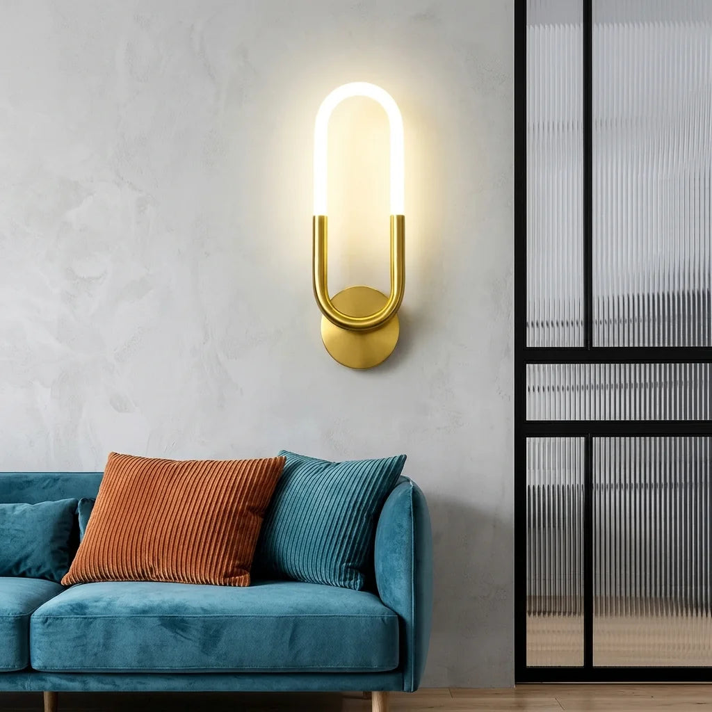 Applique LED boucle dorée au-dessus d'un canapé en velours bleu canard