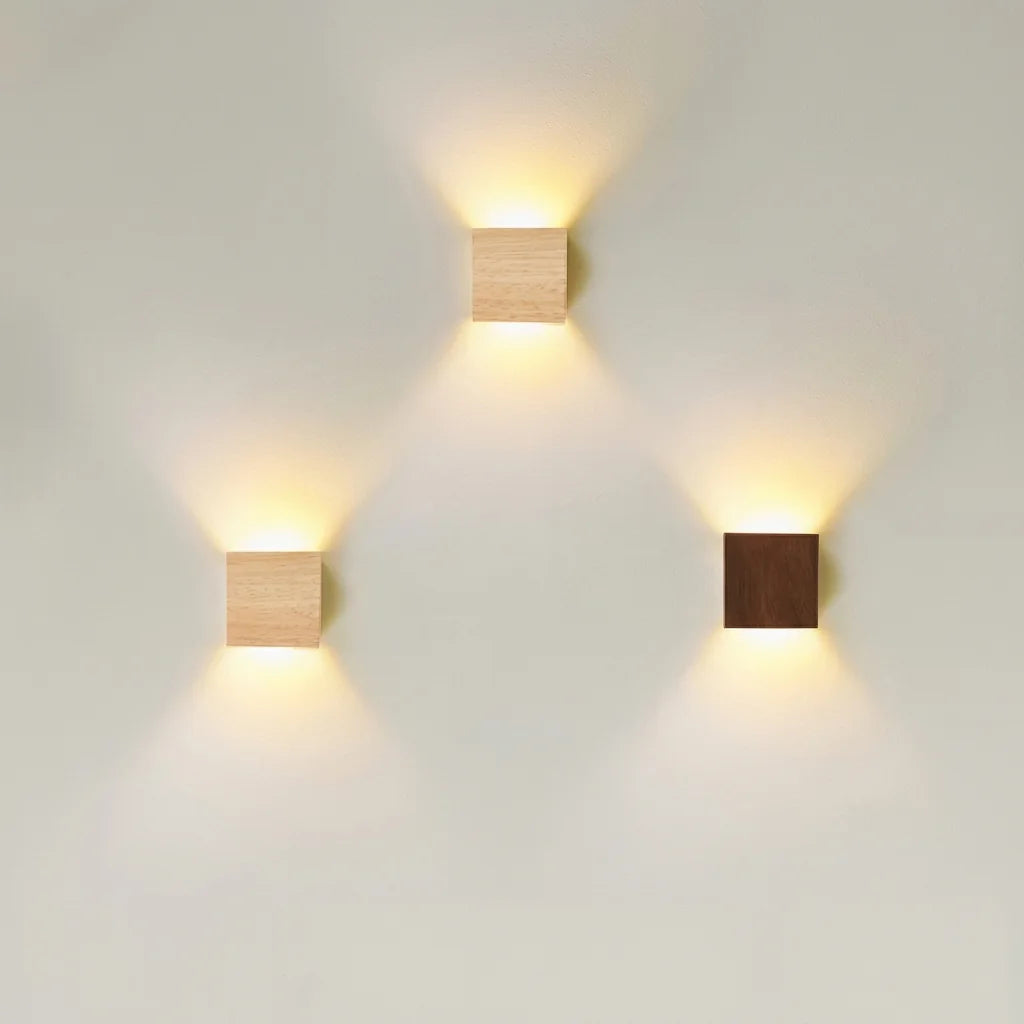 Trois appliques LED carrées bois clair et noyer sur un mur blanc