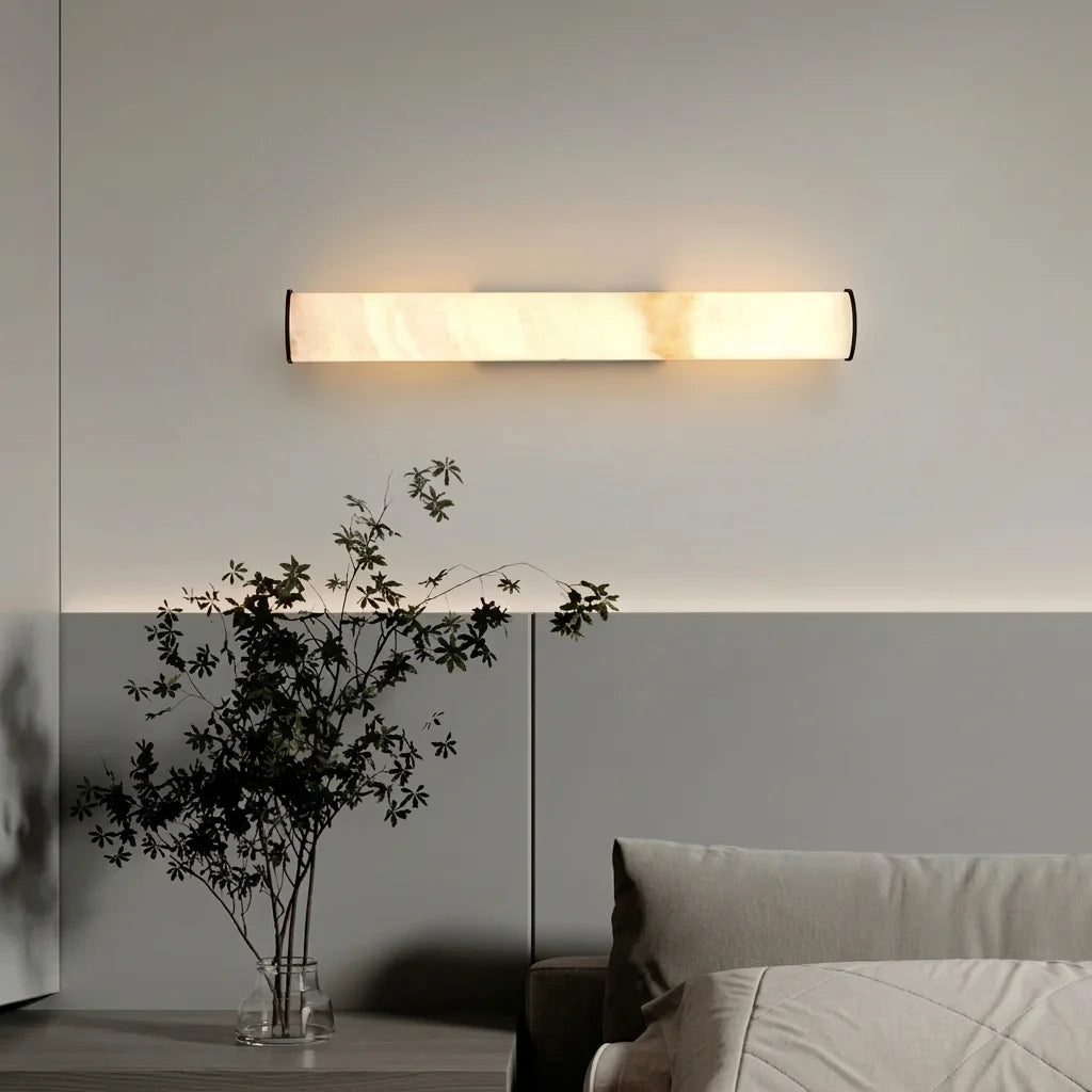 Applique cylindre effet marbre posée à l'horizontale au-dessus d'un lit