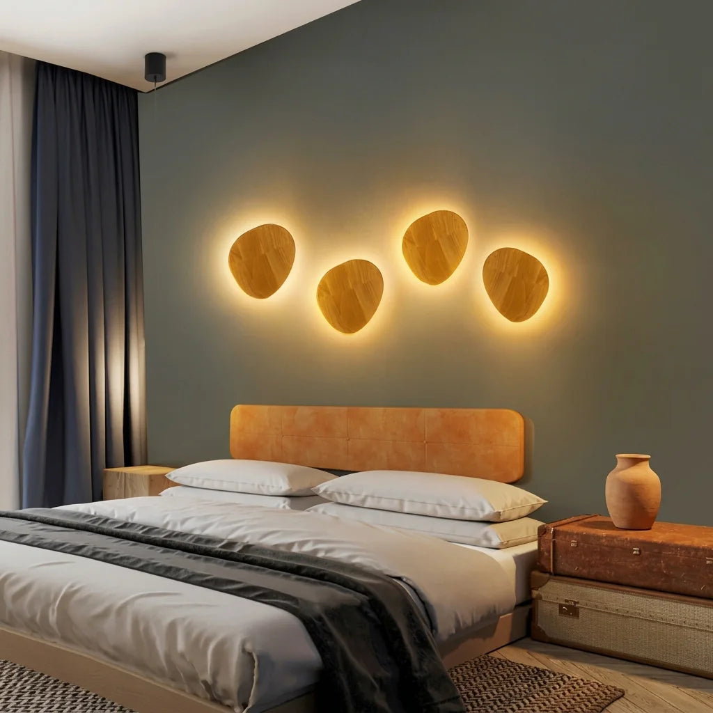 Quatre appliques galet en bois au-dessus d'une tête de lit orange