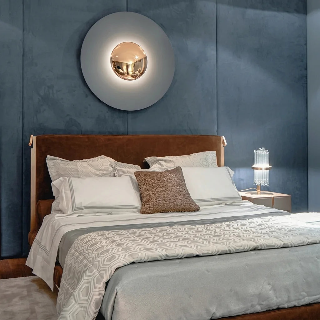 Applique disque minimaliste au-dessus d'une tête de lit sur mur bleu velours