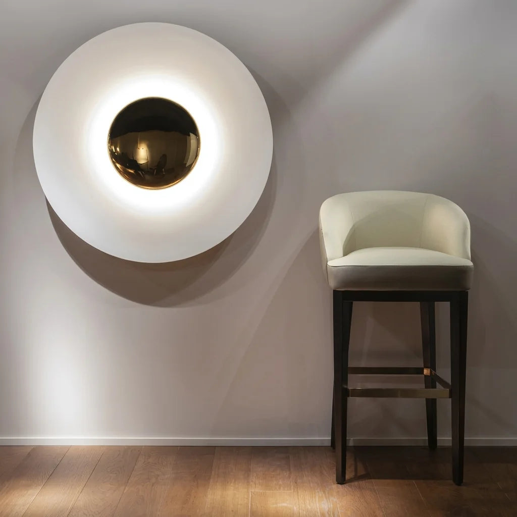 Applique disque blanche à côté d'un tabouret de bar, parquet chêne