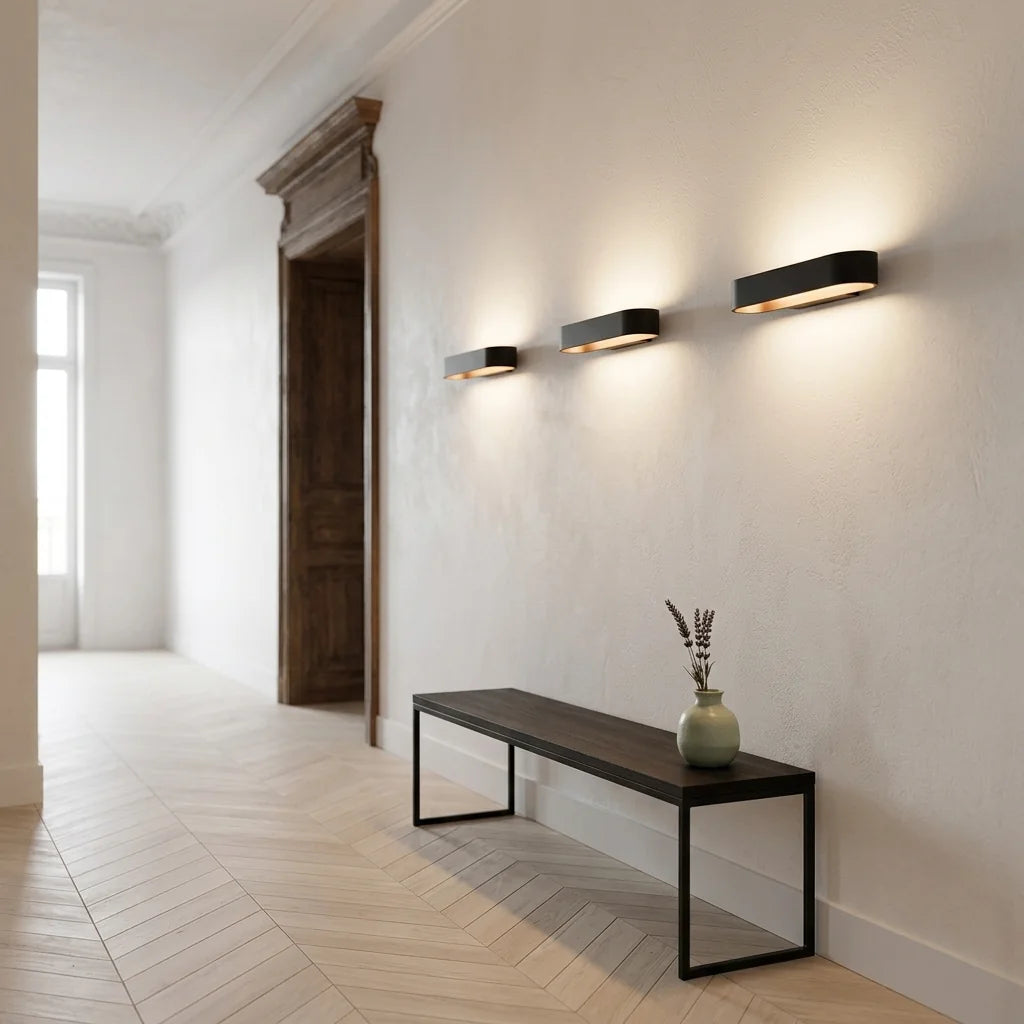 Trois appliques LED ovales noires alignées dans un couloir