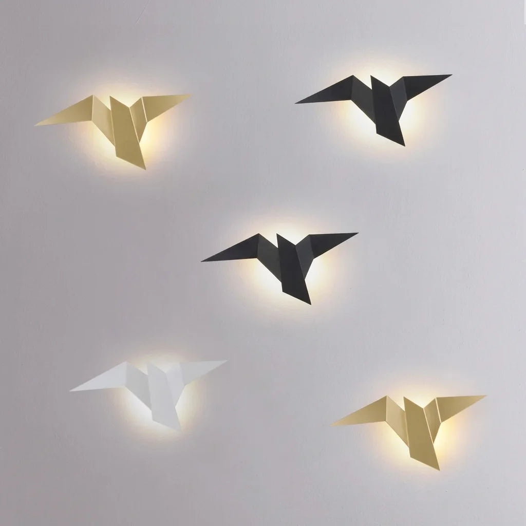Envol d'appliques oiseau dorées, noires et blanche sur un mur gris clair