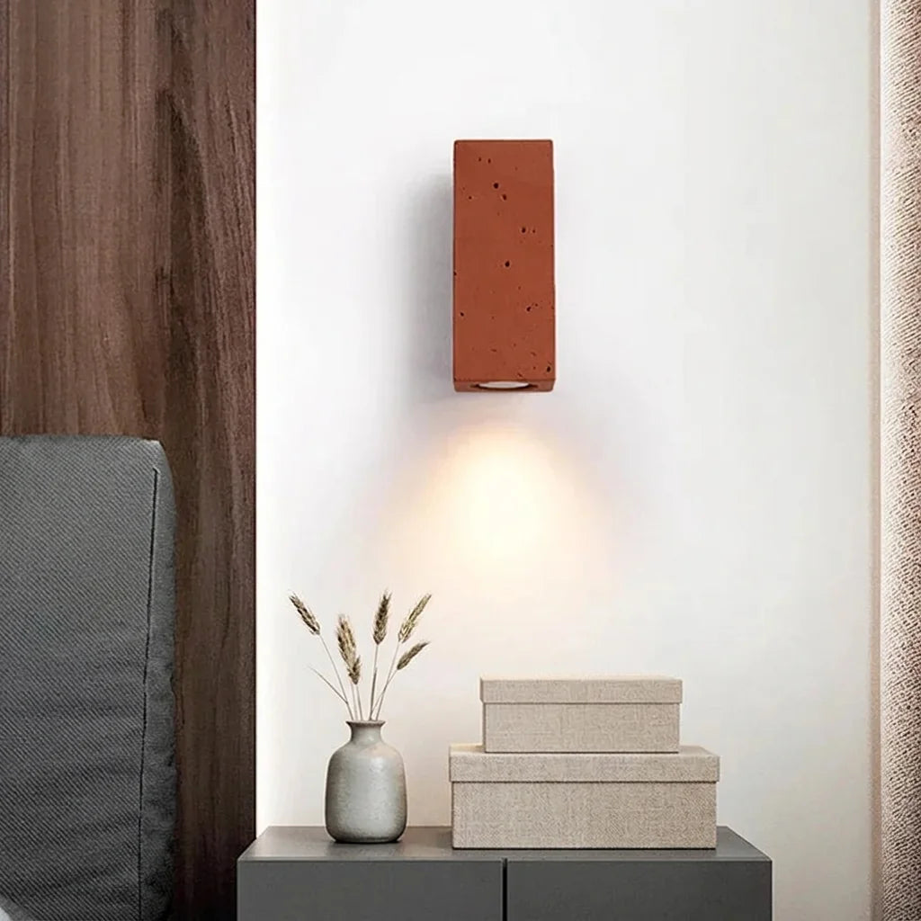 Applique carrée en pierre rouge brique au-dessus d'une console de chevet
