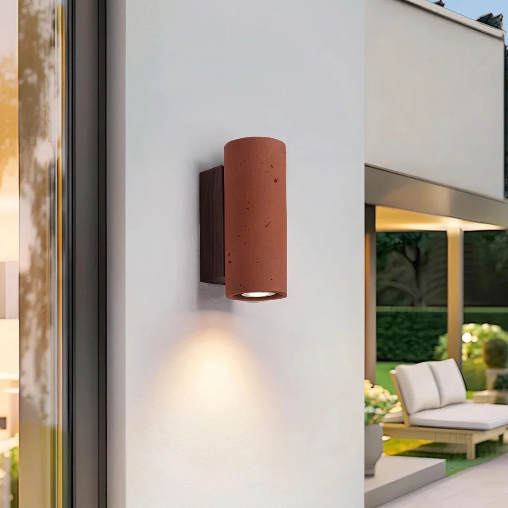 Applique ronde en pierre rouge brique sur une façade blanche près d'une terrasse