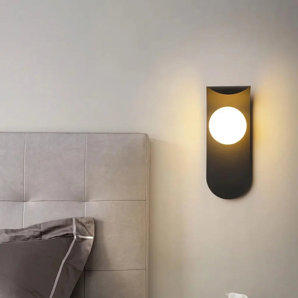 Applique LED noire à globe à côté d'une tête de lit capitonnée grise