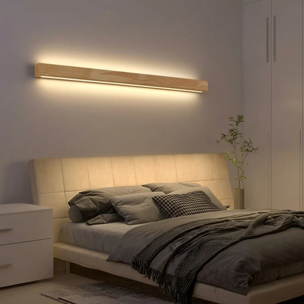 Longue réglette LED en bois au-dessus d'une tête de lit capitonnée