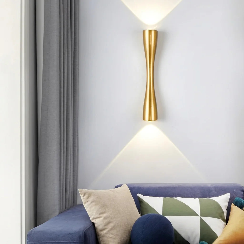 Applique sablier dorée au-dessus d'un canapé bleu dans un salon