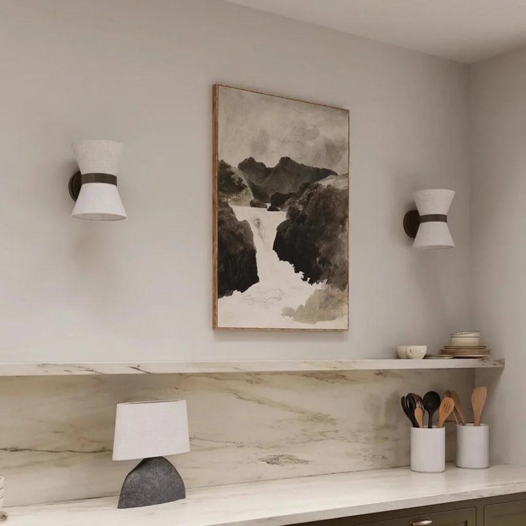 Deux appliques sablier en lin encadrant un tableau au-dessus d'un plan en marbre