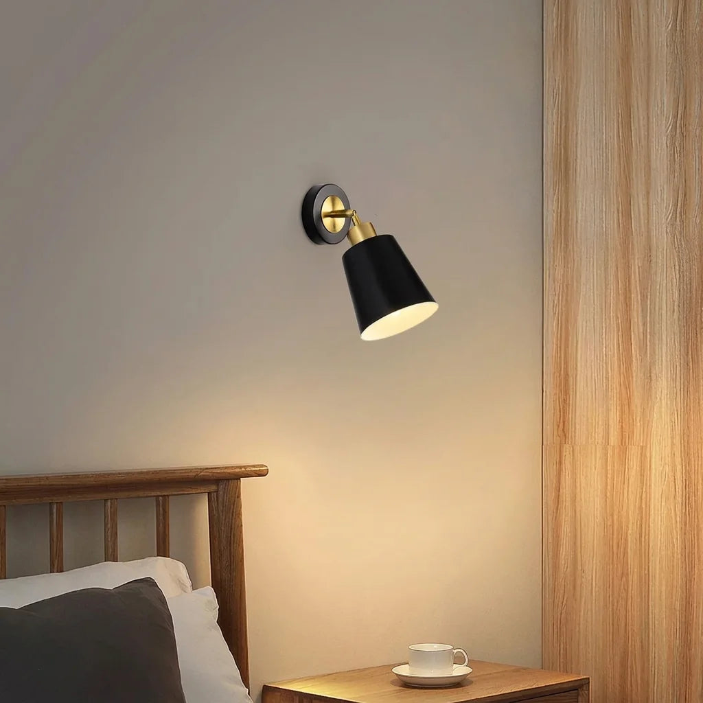 Applique spot cône noir allumée au-dessus d'une table de chevet en bois