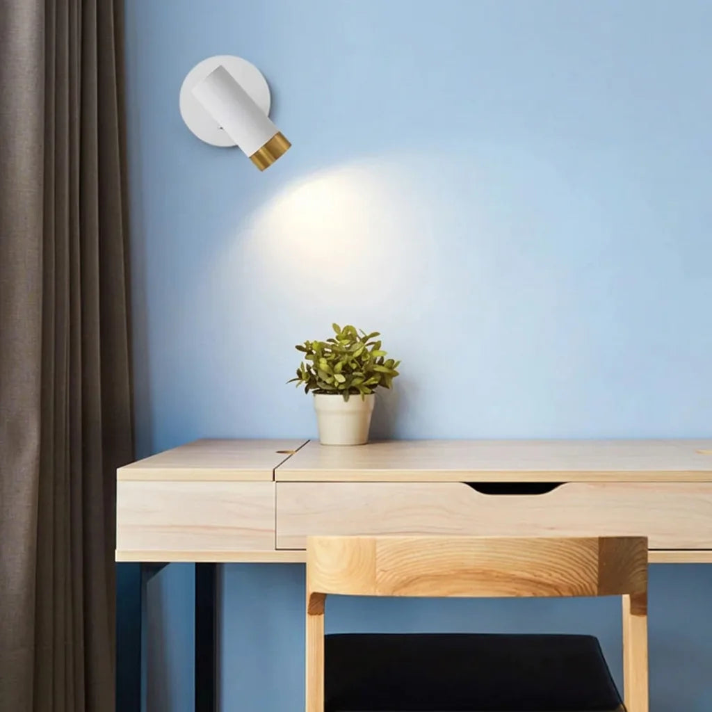Spot cylindre blanc et or orienté vers un bureau en bois clair