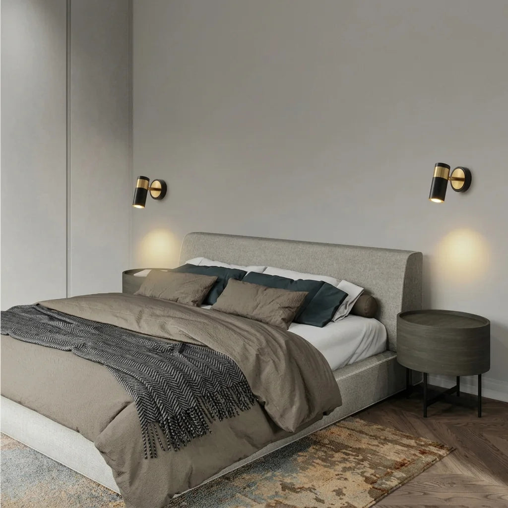 Deux spots cylindre noir et or de part et d'autre d'un lit