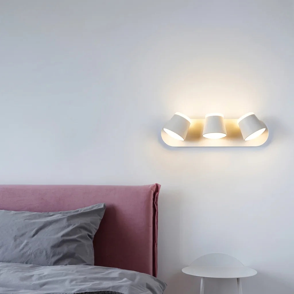 Applique blanche à trois têtes au-dessus d'une tête de lit rose